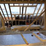 The interior of a house being built with wooden framing is prepared for roofers to install a new roof.