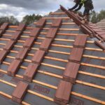 A man is working on the new roof of a house.