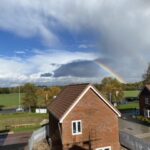 A rainbow is seen over a residential area with flat roofs.