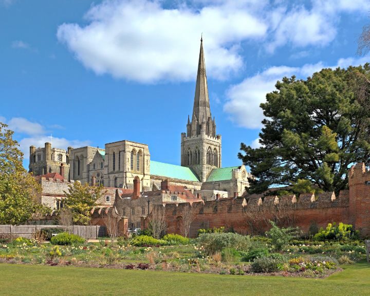 A view of a garden with a cathedral, showcasing its flat roof, in the background.