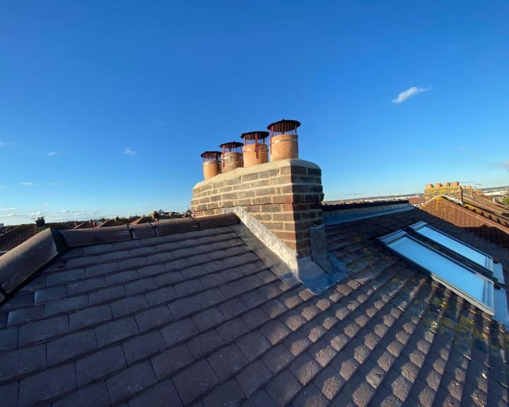 An aerial view of a roof with chimneys and skylights, indicating recent roofing repair.