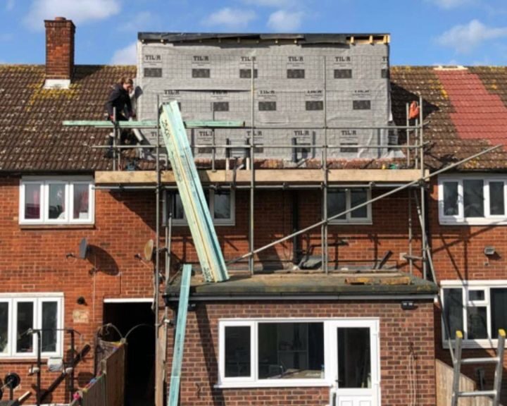 A roofer is working on a loft conversion on a residential property using scaffolding.