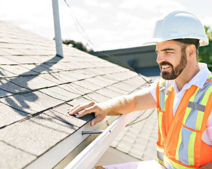 A roofer in a hard hat inspecting a new roof.