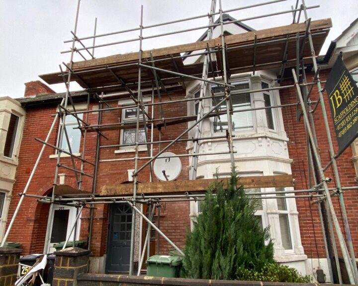 A house with scaffolding in front of it for flat roof repair.