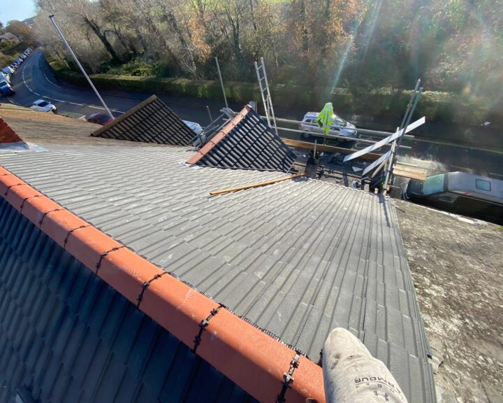 A roofer is working on the flat roof of a house.